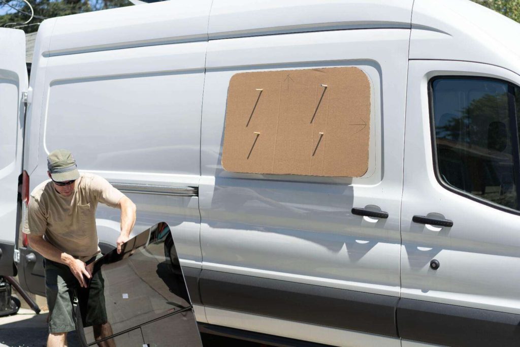 Installing CR Laurence windows on a camper van, tracing outline on van